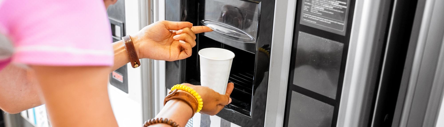 Side view of a woman filling her cup from a beverage dispensing machine