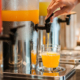 Side view of orange juice being dispensed into a cup