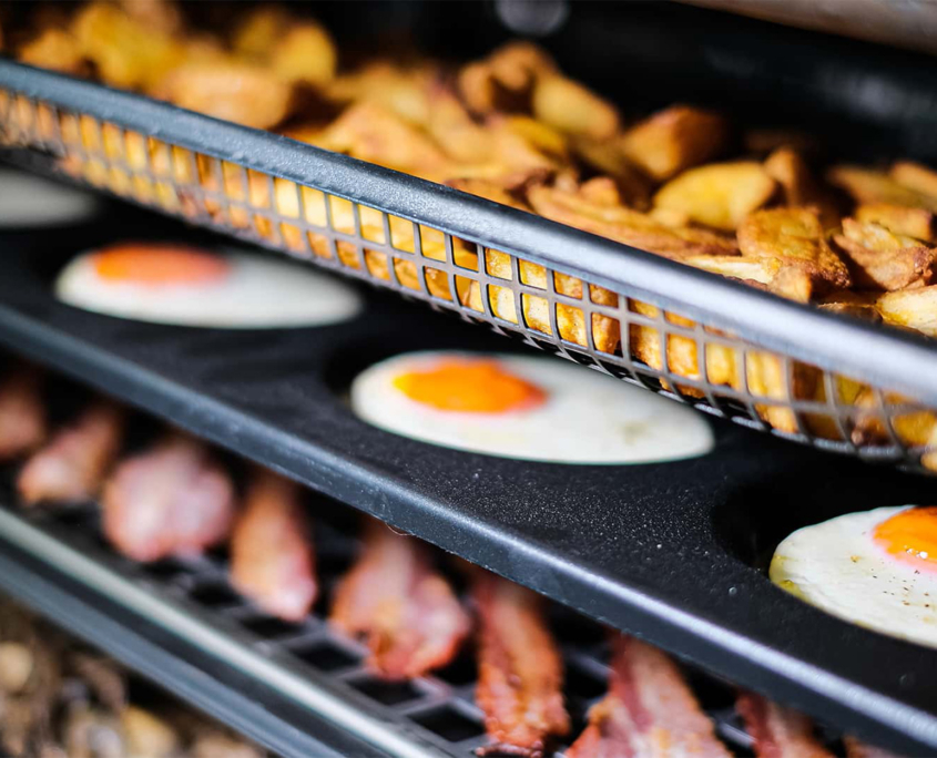 Side view of eggs and potatoes in oven tray