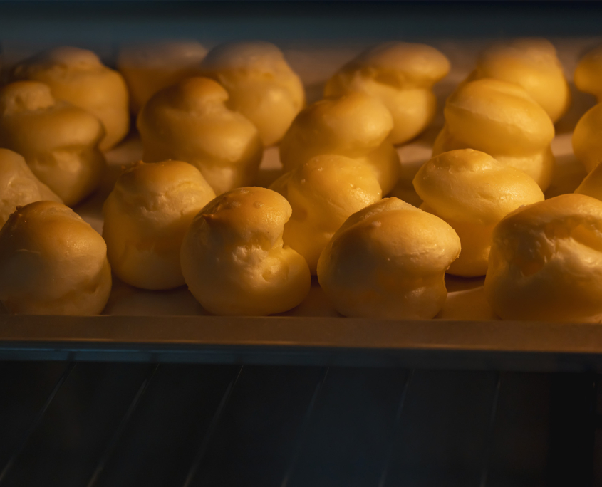 A close up of homemade choux cream baking in the oven, concept of bakery recipe