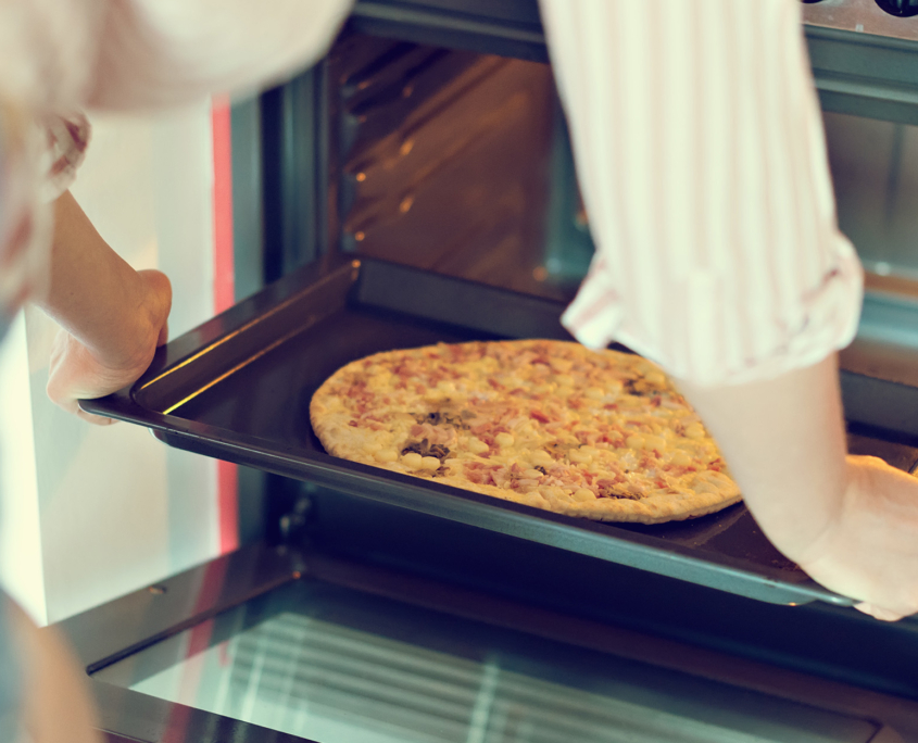 Woman preparing pizza bought in a store