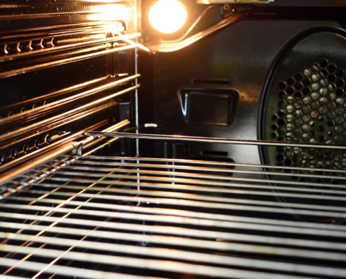 A view of the inside of an empty oven with lighting bulb and a wire rack