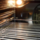 A view of the inside of an empty oven with lighting bulb and a wire rack