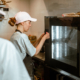 Woman in cap presses keys on control panel of oven with colleague in workshop