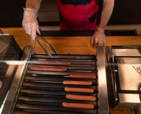 Worker at convenience store rotating hot dogs