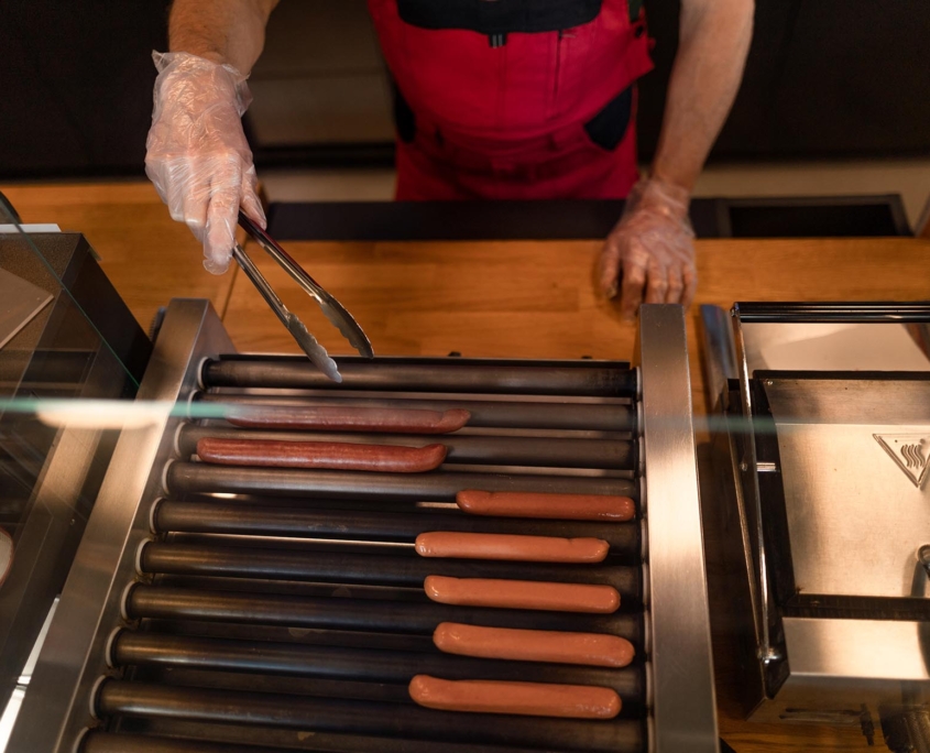 Worker at convenience store rotating hot dogs