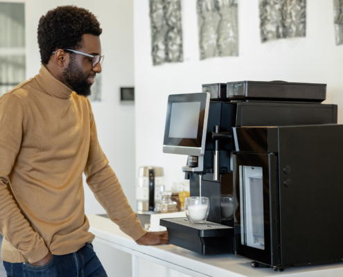 Man office worker using modern coffee machine making coffee in office