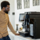 Man office worker using modern coffee machine making coffee in office